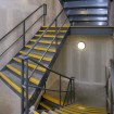 Internal fire escape stairs with chequer plate treads and contrasting yellow painted nosing complete with stringer mounted round tube 